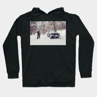 Tourist walking alone through winter forest passing off-road parked car Hoodie